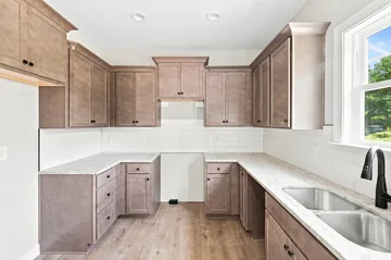Kitchen with a corner counter, tiled splashback and a window over the sink